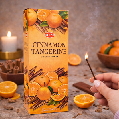 HEM Cinnamon Tangerine incense sticks box with oranges, cinnamon sticks, and a hand holding burning incense
