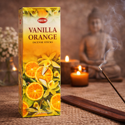 HEM Vanilla Orange incense sticks box with burning incense, candles, and Buddha decor