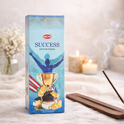 HEM Success incense sticks box with burning incense and candles on a soft neutral background