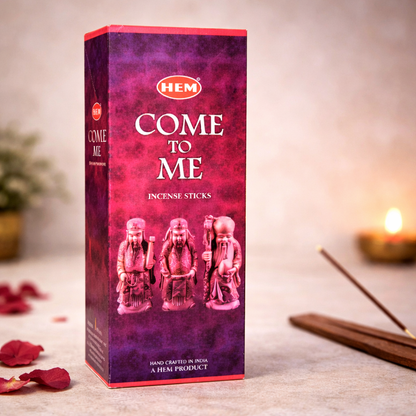 HEM Come to Me incense sticks box with rose petals and candle on a neutral background