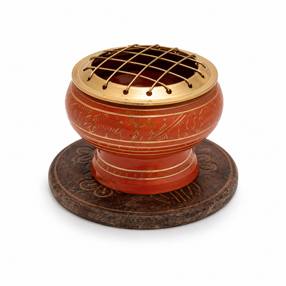 Orange decorative incense burner with gold detailing and a brass screen top, displayed on an ornate round wooden coaster against a white background.