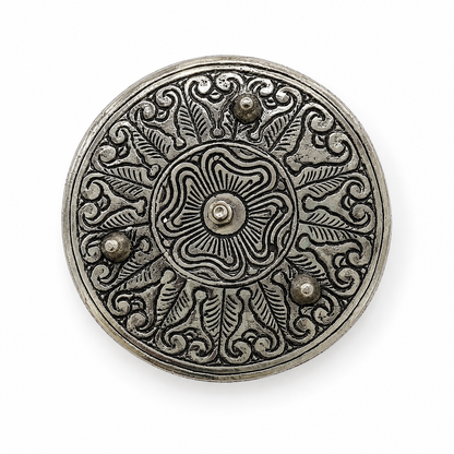 Bottom view of an antique silver incense holder featuring ornate floral and leaf engravings, a central fastener, and three raised feet on a white background.