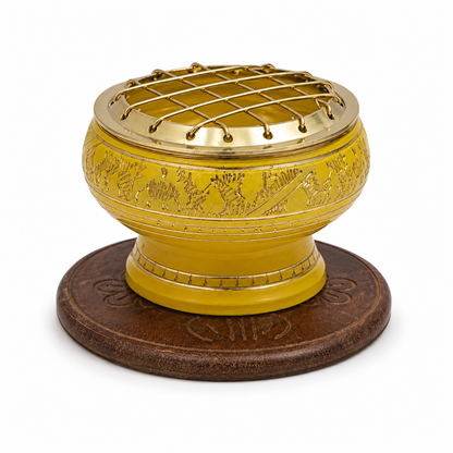 Yellow decorative incense burner with gold detailing and a brass screen top, displayed on an ornate round wooden coaster against a white background.