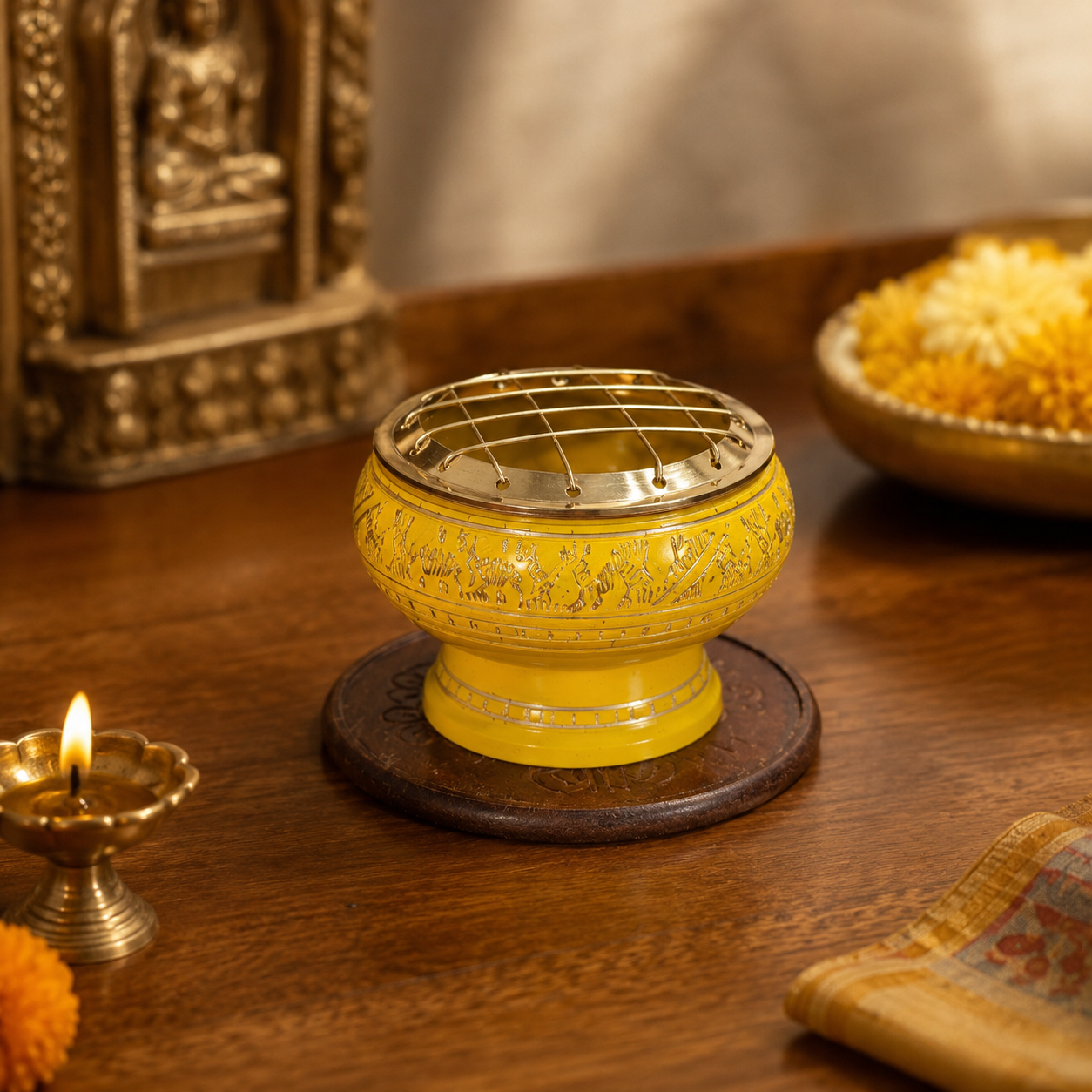 Lifestyle image of yellow and gold incense burner with brass screen and carved wooden coaster.